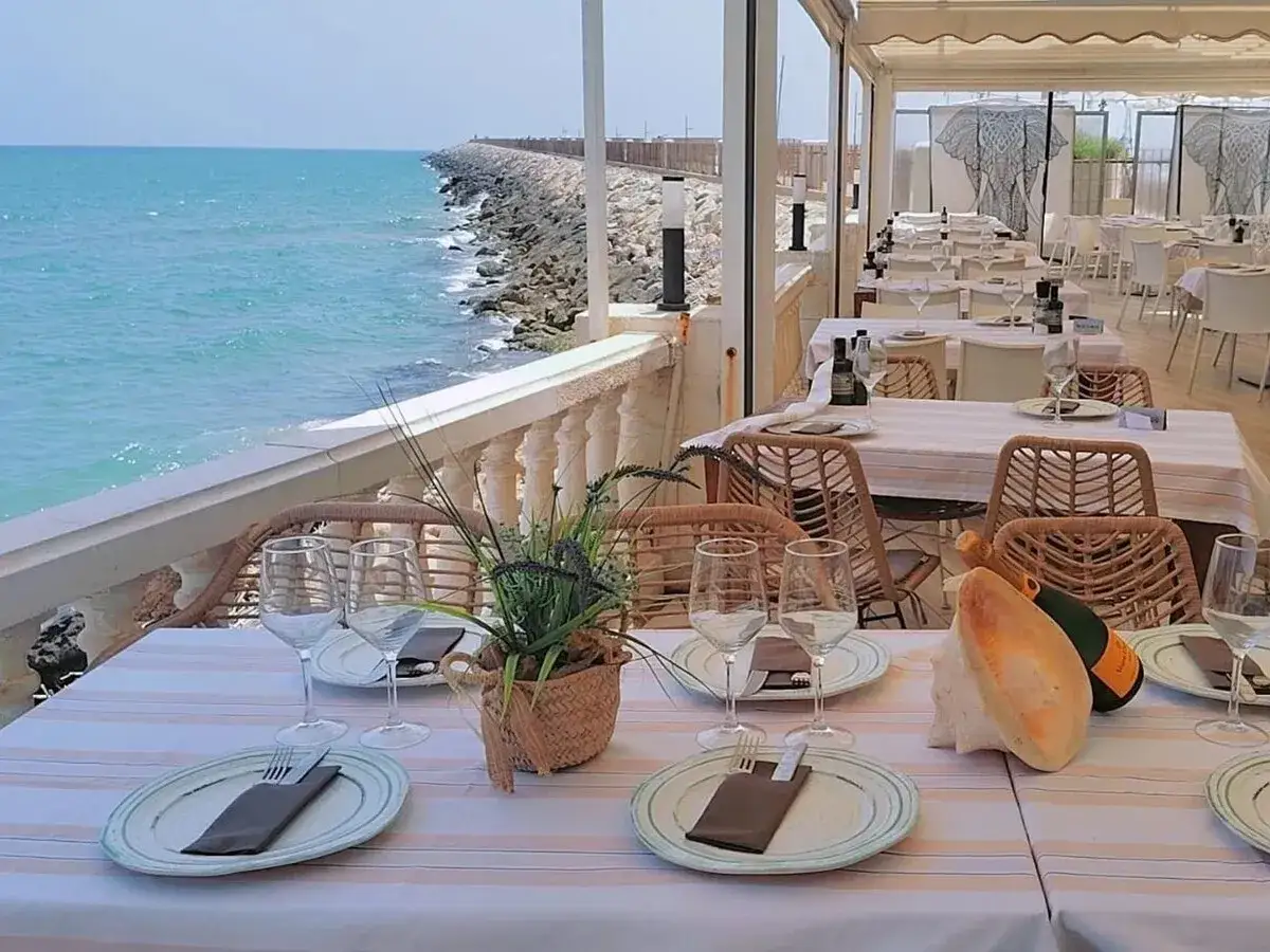 Mesas puestas para comer en Gandía, con vistas al mar Mediterráneo y un ambiente relajado.