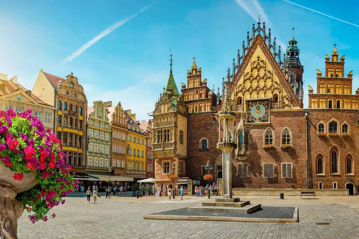 Plaza del Mercado en Breslavia, Polonia, con edificios hist&oacute;ricos y flores vibrantes.