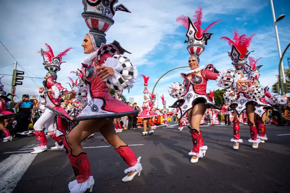 Desfile de carnaval con bailarines en trajes brillantes y elaborados sombreros. &iexcl;Un destino ideal donde viajar en febrero para vivir esta fiesta!