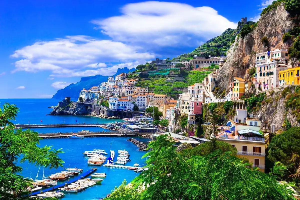 Un pueblo costero italiano con casas coloridas en la ladera, un puerto lleno de barcos y el mar azul. &iexcl;Un destino perfecto donde viajar en junio!