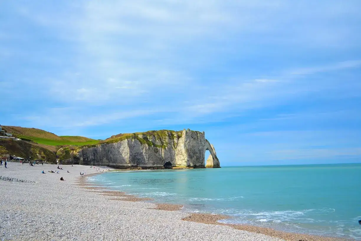 Acantilados de &Eacute;tretat, un lugar imprescindible que ver en Normand&iacute;a. Playa de guijarros, mar turquesa y un arco natural imponente.