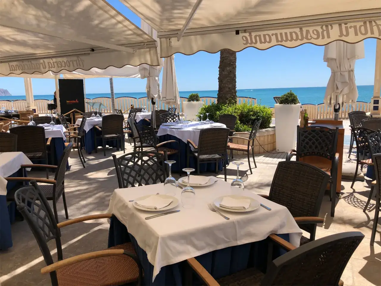 Mesas puestas en un restaurante con vistas al mar, ideal para saber donde comer en Altea.