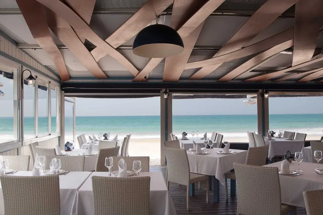 Mesas puestas en un restaurante frente al mar, ideal para saber donde comer en Conil y disfrutar de la brisa marina.