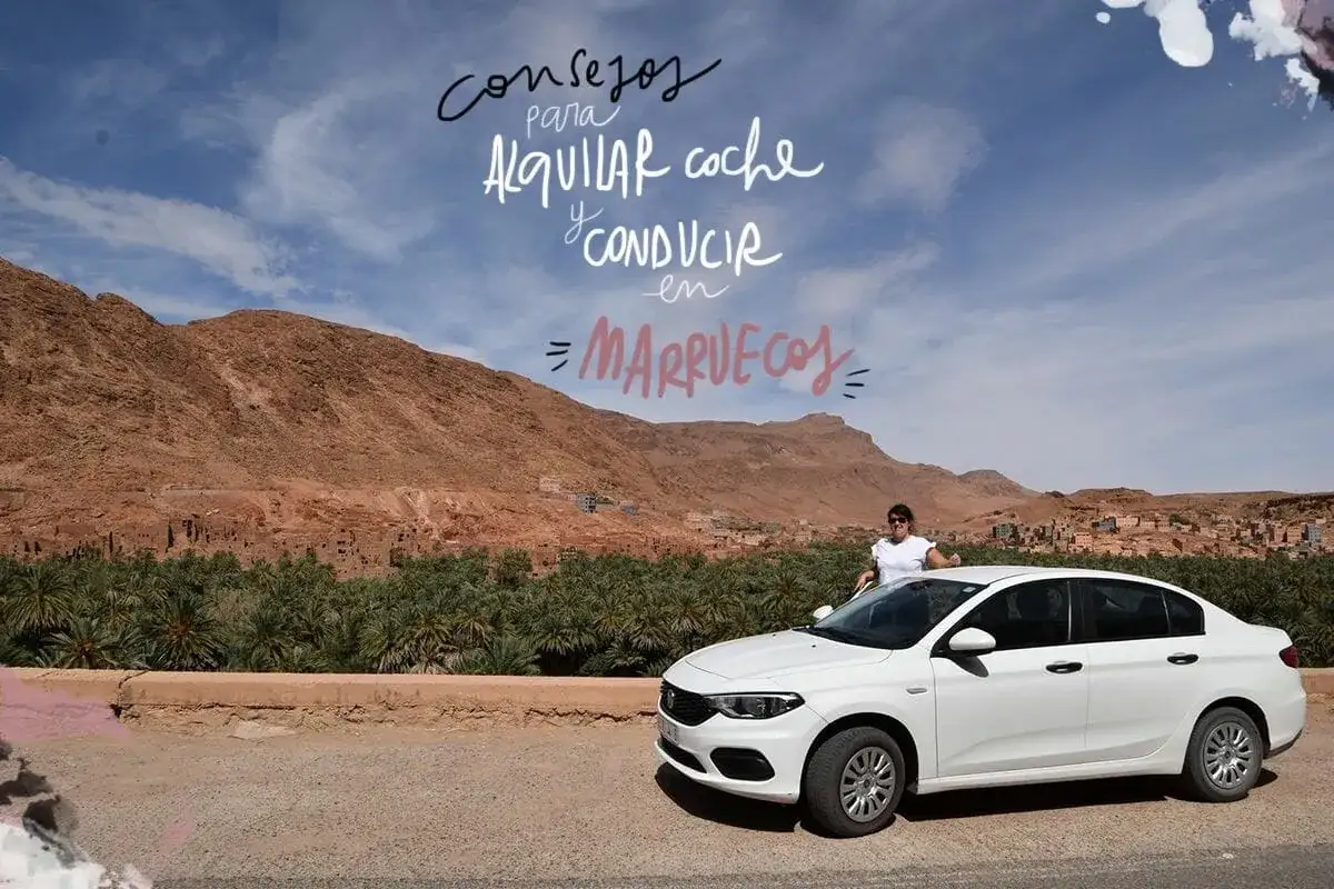 Mujer junto a coche blanco en Marruecos, lista para viajar. Paisaje des&eacute;rtico con palmeras y monta&ntilde;as.
