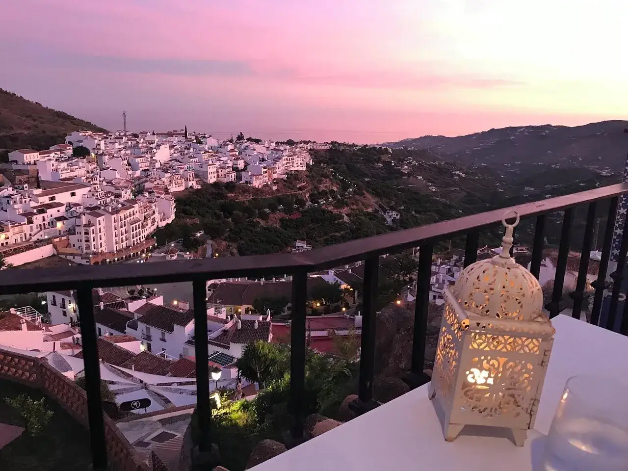 Atardecer rosado sobre Frigiliana. Una linterna ilumina la mesa, perfecta para decidir donde comer en Frigiliana.