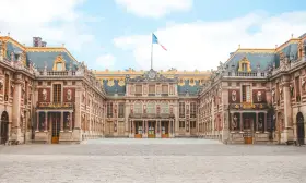Palacio de Versalles, una visita obligada si buscas qué ver en París en 2 días. Majestuosa arquitectura y bandera francesa ondeando.