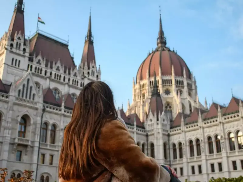Mujer con abrigo de pelo admira el Parlamento de Budapest, un destino ideal donde viajar en noviembre en Europa.