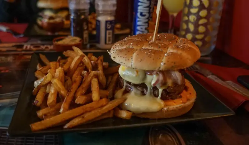 Jugosa hamburguesa con queso fundido y patatas fritas, ideal para saber donde comer en Carcassonne.